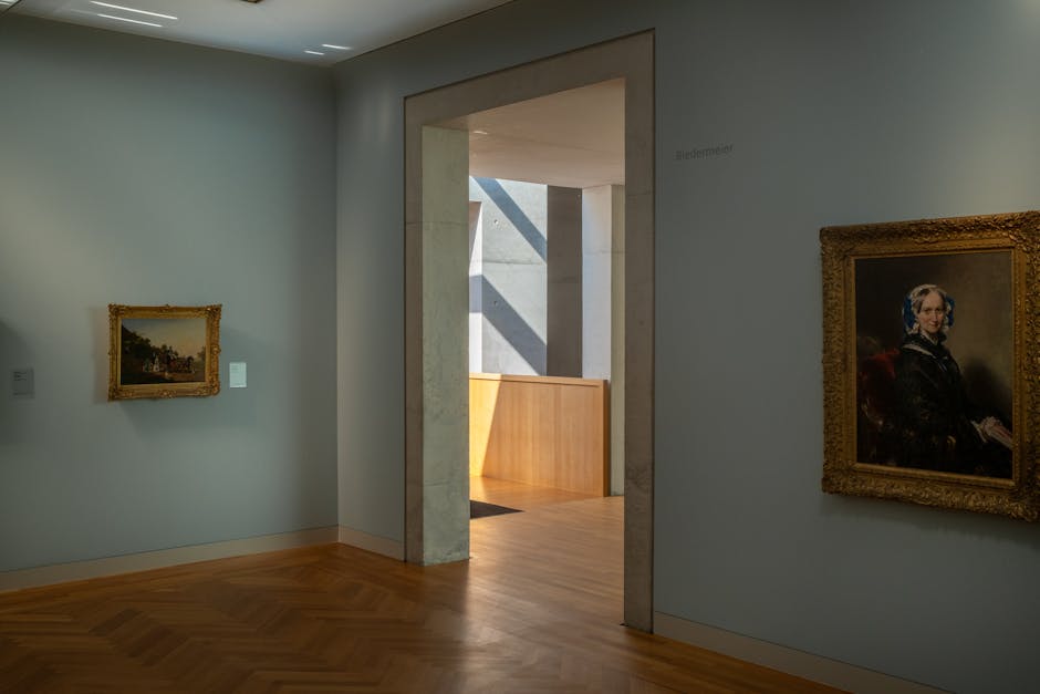 A well-lit museum room displaying classic framed paintings with a wooden floor.