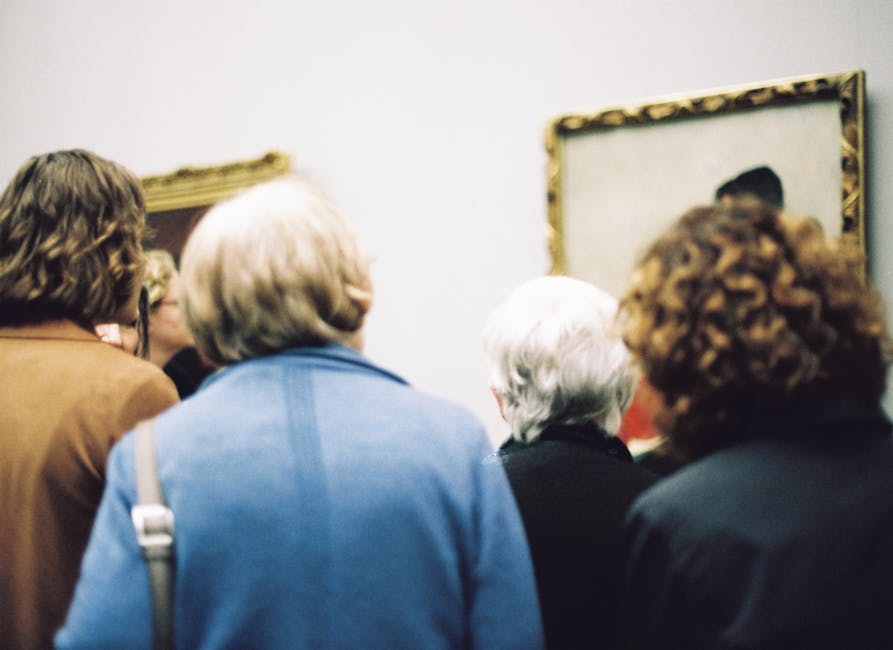 A group of adults viewing paintings in an art gallery with a focus on a framed artwork.
