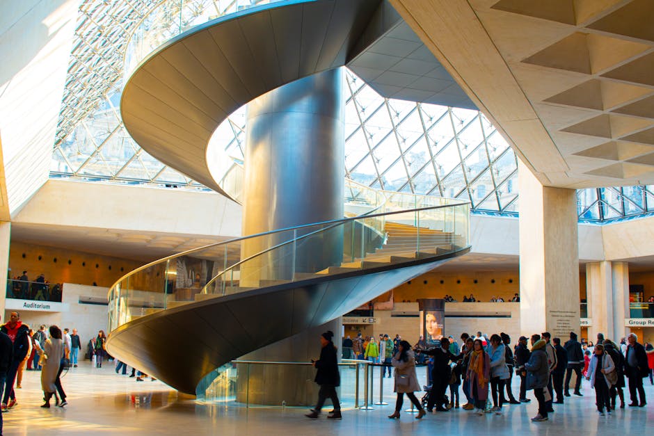 Visitors gather near a stunning spiral staircase at the Louvre Museum, Paris, France.