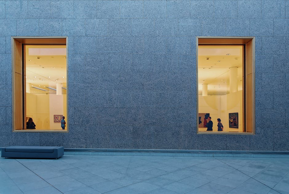 View of a modern art gallery exterior with large windows framing an exhibition.