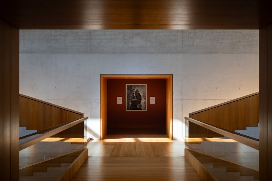Contemporary museum interior with wooden staircases and a central artwork display.